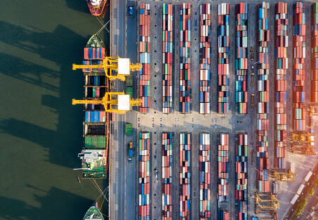 Top view of international port with Crane loading containers in import export business logistics.